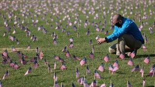 WASHINGTON, DC - SEPTEMBER 22: Chris Duncan, whose 75 year old mother Constance died from COVID on her birthday, photographs a COVID Memorial Project installation of 20,000 American flags on the National Mall as the United States crosses the 200,000 lives lost in the COVID-19 pandemic September 22, 2020 in Washington, DC. The flags are displayed on the grounds of the Washington Monument facing the White House.