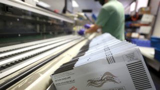 Mail-in ballots sit in a sorting machine.