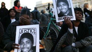 Protestors carry signs with a picture of slain 22-year-old Oscar Grant III during a demonstration at Oakland City Hall.