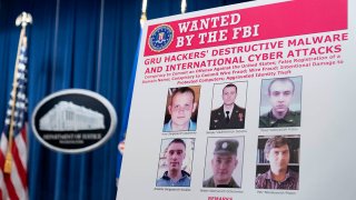 A poster shows six Russian military intelligence officers wanted by the U.S. government. The U.S. Department of Justice announced charges against the officers for their alleged involvement in a vast hacking campaign that targeted the Olympics, foreign elections and U.S. businesses, on Oct. 19, 2020, in Washington.