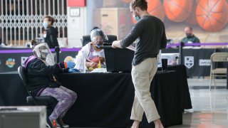LOS ANGELES, CALIFORNIA – OCTOBER 25: A voter (R) walks toward an election official who is wearing a face shield, mask and gloves at a Vote Center located at the Staples Center on the first weekend of early in-person voting on October 25, 2020 in Los Angeles, California. Voters in Los Angeles County are now able to vote in person at any Vote Center located within the county. (Photo by Mario Tama/Getty Images)