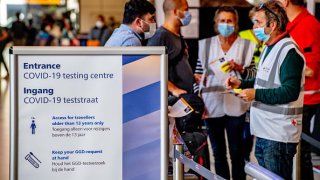 Travelers wear face masks as a preventive measure at Schiphol airport.