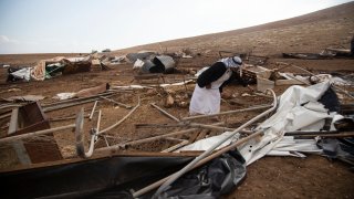A Palestinian sifts through destroyed tents