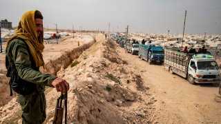 A Kurdish fighter looks on as a convoy of trucks transporting Syrian women and children suspected of being related to Islamic State (IS) group leaves the Kurdish-run al-Hol camp, after being released to return to their homes, in the al-Hasakeh governorate in northeastern Syria, on October 28, 2020. Earlier this week, an Oregon man was indicted Thursday after authorities said he supported the Islamic State group by distributing articles on how to kill and maim with a knife and encouraging readers to carry out attacks.