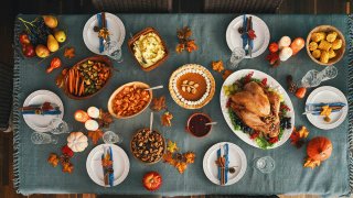 Thanksgiving Party Table Setting. Traditional Holiday Dinner with Stuffed Turkey, Roasted Potatoes, Cranberry Sauce, Vegetables and Pumpkin Pie