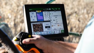 A worker uses a yield monitor in a Deere & Co. combine while harvesting corn at a farm in Union Springs, New York, U.S., on Saturday, Nov. 7, 2020.