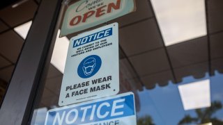 Social-distancing and mask wearing signs on a storefront during the 2020 Presidential election in Miami, Florida, U.S., on Wednesday, Nov. 4, 2020.