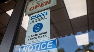 Social-distancing and mask wearing signs on a storefront during the 2020 Presidential election in Miami, Florida, U.S., on Wednesday, Nov. 4, 2020.