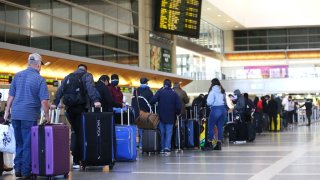 Travelers wait in line to check in for a flight