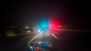 Car driving down road with red and blue lights