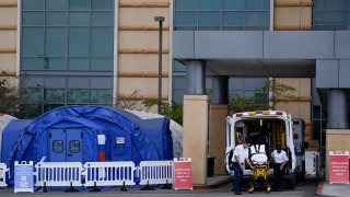 Medical workers remove a stretcher from an ambulance near medical tents outside the emergency room at UCI Medical Center, Thursday, Dec. 17, 2020, in Irvine, California.