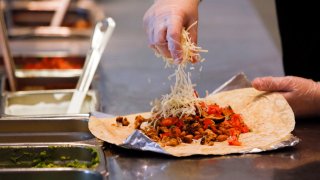 A employee sprinkles cheese on a burrito at a Chipotle Mexican Grill restaurant in Hollywood, California.