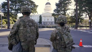 Members of the California National Guard walk past the California state Capitol in Sacramento, Calif., Wednesday, Jan. 20, 2021.