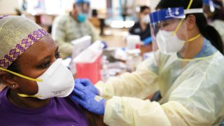 In this Jan. 7, 2021, nurse Bethlehem Gurmu (L) receives a dose of the Moderna COVID-19 vaccine from public health nurse Kathy Luu as staff members are vaccinated at the Ararat Nursing Facility in the Mission Hills neighborhood of Los Angeles, California.