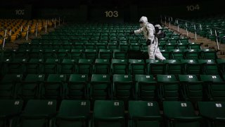 Alexander Espinoza of V&G Cleaning Services uses an electromagnetic sanitizer with hospital-grade disinfectant to sterilize the George Mason Patriots men's basketball spectator seating bowl against the novel coronavirus after their men's NCAA basketball game against the La Salle Explorers at Eagle Bank Arena on January 13, 2021 in Fairfax, Virginia.