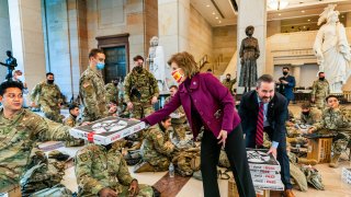 Rep. Vicky Hartzler, R-Mo., and Rep. Michael Waltz, R-Fla., hand pizzas to members of the National Guard gathered at the Capitol Visitor Center, Wednesday, Jan. 13, 2021, in Washington, D.C., as the House of Representatives continues with its fast-moving House vote to impeach President Donald Trump, a week after a mob of Trump supporters stormed the U.S. Capitol.