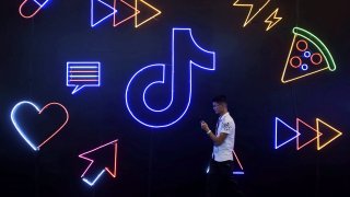 A man holding a phone walks past a sign of Chinese company ByteDance’s app TikTok, known locally as Douyin, at the International Artificial Products Expo in Hangzhou, Zhejiang province, China October 18, 2019.