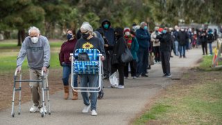 David Aberson, 86, left, and his wife Dori, 75, make their way with others in the by appointment only line to get vaccine shots to protect against the coronavirus at the Balboa Sports Complex in Encino. Dori Aberson said that they were not able to get appointments for both of them on the same day and that she has to come back the next day to get her vaccine shot.