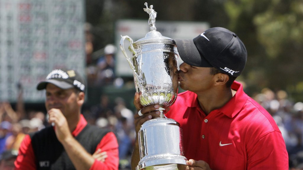 This June 16, 2008, photo shows Tiger Woods kissing the championship trophy after winning the US Open against Rocco Mediate, left, after a sudden death hole following an 18-hole playoff round at Torrey Pines Golf Course, in San Diego.