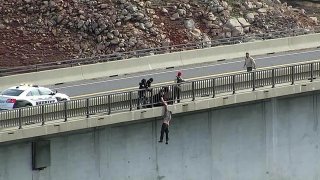 This drone photo provided by the Tuolumne County Sheriff shows personnel from multiple agencies grabbing a man who is attempting to jump from the Parrotts Ferry Bridge, Monday, Feb. 8, 2021. Authorities say the man trying to jump off the bridge was saved when a sheriff's deputy gripped his arm as the man dangled 150 feet above the waters of New Melones Lake in the Sierra Nevada. He was taken to a hospital for a mental evaluation
