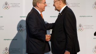 FILE - In this Saturday, May 4, 2019 file photo, International Olympic Committee President Thomas Bach, left, shakes hands with Australian Olympic Committee (AOC) President John Coates at the AOC annual general meeting in Sydney, Australia. The Australian Olympic bid is on a fast-track to host the 2032 Olympics Wednesday Feb. 24, 2021, after the International Olympic Committee executive board gave Queensland “preferred bidder” status, 11 years ahead of the games.