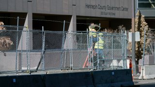 Workers install barbed wire on fencing outside the Hennepin County Government Center
