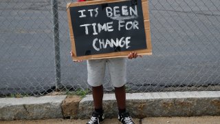 Dewayne Henry, 14, holds a sign as he protests outside of Mystic Valley Regional Charter School in Malden, MA