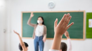 students in class raise hands