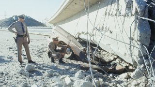 California Highway Patrol officers look at smashed remains of a pickup truck that was crushed under tons of concrete when part of the 5 Freeway overpass collapsed during an earthquake.