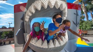 Children wearing face masks play at Legoland California Resort.