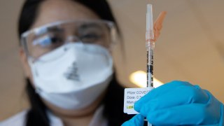Woman in mask with syringe of coronavirus vaccine
