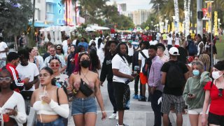 People walk along Ocean Drive on March 21, 2021 in Miami Beach, Florida. College students have arrived in the South Florida area for the annual spring break ritual, prompting city officials to impose an 8pm to 6am curfew as the coronavirus pandemic continues.