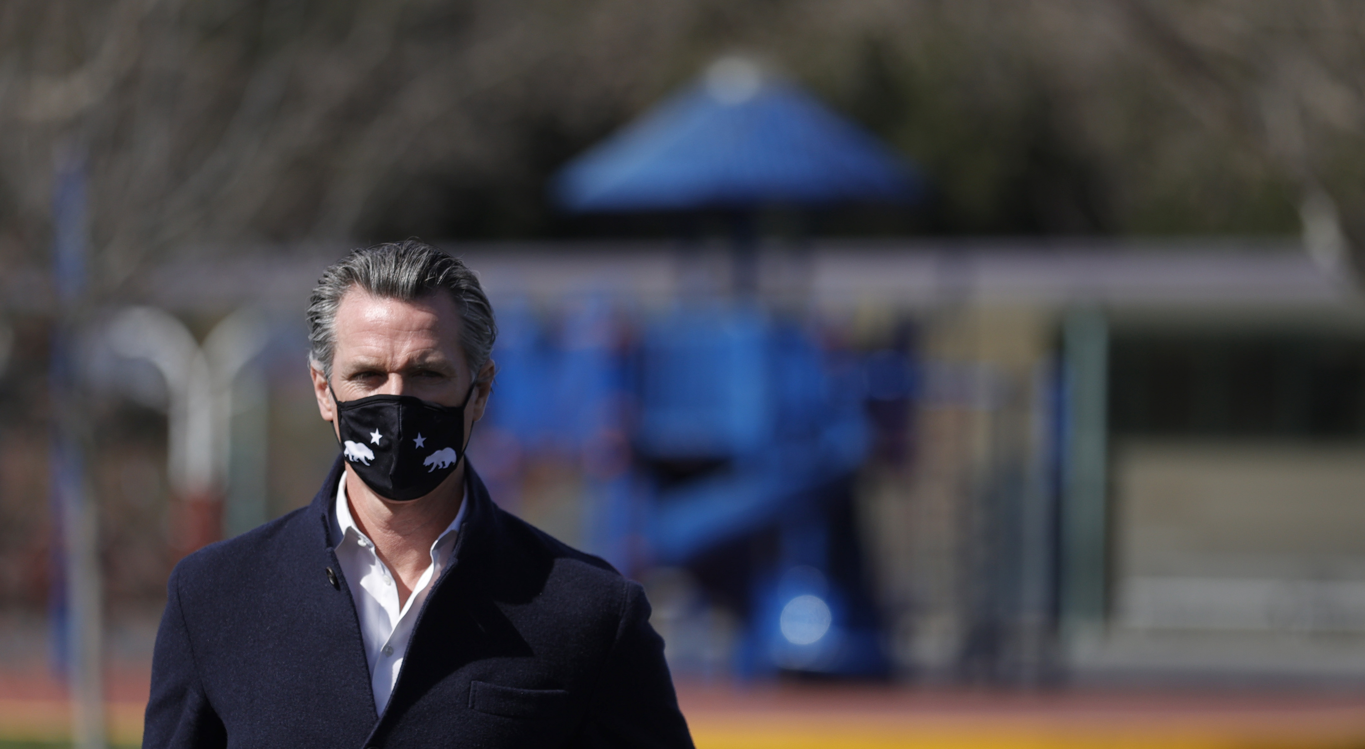 California Gov. Gavin Newsom looks on.