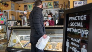 A person wearing a protective mask picks up an order at a cafe.