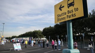 People wait in line to receive the COVID-19 vaccine at a mass vaccination site in a parking lot for Disneyland Resort.