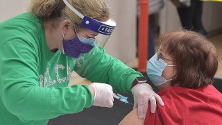 elaware County Medical Service Corp volunteer Jennifer Moore of Secane, PA. gives Marianne Lawn of Upper Darby her first Moderna vaccine at a clinic held at Upper Darby High School