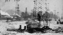 Flood waters rushing across inundated oil fields after rains caused Los Angeles & Santa Ana Rivers to overflow their banks.