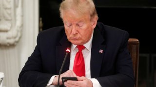 President Donald Trump uses a mobile phone during a roundtable discussion on the reopening of small businesses in the State Dining Room at the White House in Washington, U.S., June 18, 2020.