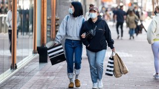 Shoppers wearing protective masks carry bags on Market Street in San Francisco, California, on Wednesday, April 14, 2021.