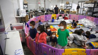 In this March 30, 2021, file photo, young unaccompanied migrants, from ages 3 to 9, watch television inside a playpen at the U.S. Customs and Border Protection facility, the main detention center for unaccompanied children in the Rio Grande Valley, in Donna, Texas.