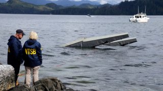 FILE - In this photo provided by the National Transportation Safety Board, NTSB investigator Clint Crookshanks, left, and member Jennifer Homendy stand near the site of some of the wreckage of the DHC-2 Beaver, Wednesday, May 15, 2019, that was involved in a midair collision near Ketchikan, Alaska, a couple of days earlier. The pilots of two Alaskan sightseeing planes that collided in midair couldn't see the other aircraft because airplane structures or a passenger blocked their views, and they didn't get electronic alerts about close aircraft because safety systems weren't working properly. That's what the staff of the National Transportation Safety board found in their investigation.