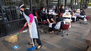 MANHATTEN BEACH, CA -JULY 29, 2020: Anna Phan sweeps outside of Posh Nails in Manhattan Beach as customers receive manicures and pedicures. The salon had to move outdoors in order to maintain a safe working environment due to the coronavirus outbreak. (Mel Melcon / Los Angeles Times via Getty Images)