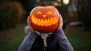 A girl with Halloween pumpkin in front of her head