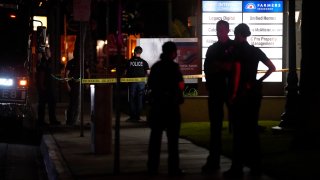 Police officers stand outside a business building where a shooting occurred in Orange, Calif., Wednesday, March 31, 2021. Police say several people were killed, including a child, and the suspected shooter was wounded by police.
