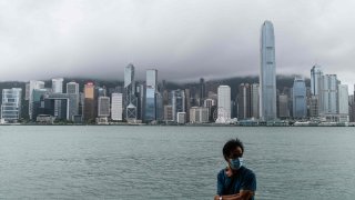 A man wearing a protective face mask stands on Kowloon’s Tsim Sha Tsui waterfront that faces Victoria Harbour in Hong Kong.