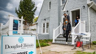 A real estate agent stands in the doorway as Giovani and Nicole Quiroz of Brooklyn, New York visit an open house in West Hempstead, New York on April 18, 2021.