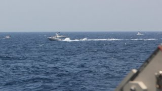 In this image provided by the U.S. Navy, an Iranian Islamic Revolutionary Guard Corps Navy (IRGCN) fast in-shore attack craft (FIAC), a type of speedboat armed with machine guns, speeds near U.S. naval vessels transiting the Strait of Hormuz, Monday, May 10, 2021. U.S. officials say a group of 13 armed speedboats of Iran’s Revolutionary Guard made “unsafe and unprofessional” high-speed maneuvers toward U.S. Navy vessels in the Strait of Hormuz on Monday. A U.S. Coast Guard cutter fired warning shots when two of the Iranian boats came dangerously close.