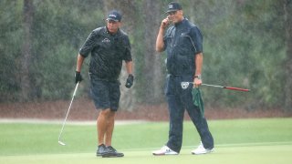 Phil Mickelson and NFL player Tom Brady of the Tampa Bay Buccaneers stand in the rain on the 13th green during The Match: Champions For Charity at Medalist Golf Club on May 24, 2020 in Hobe Sound, Florida.