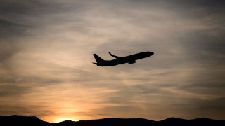 A commercial plane takes off after sunset from Geneva Airport, Switzerland.