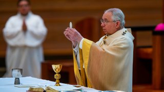 Archbishop Jose H. Gomez holds a Communion wafer